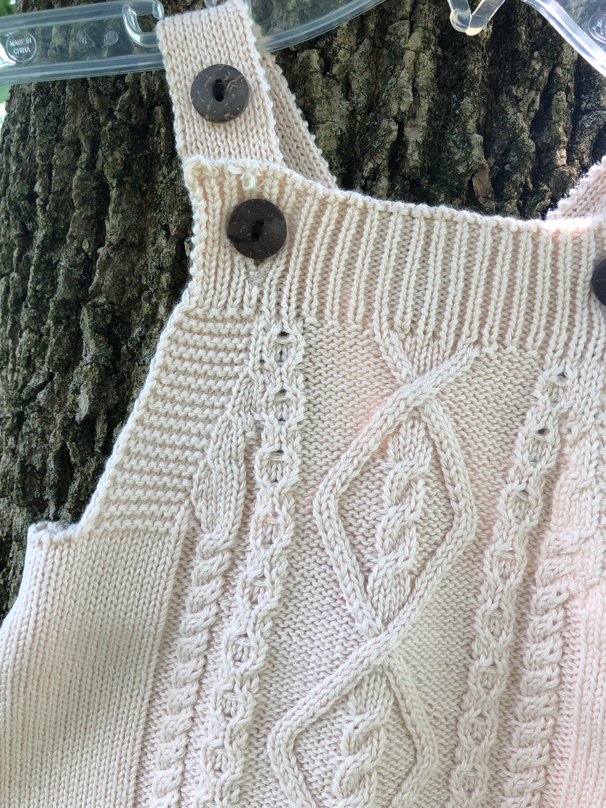 outdoor photo of knit baby romper taken on  tree